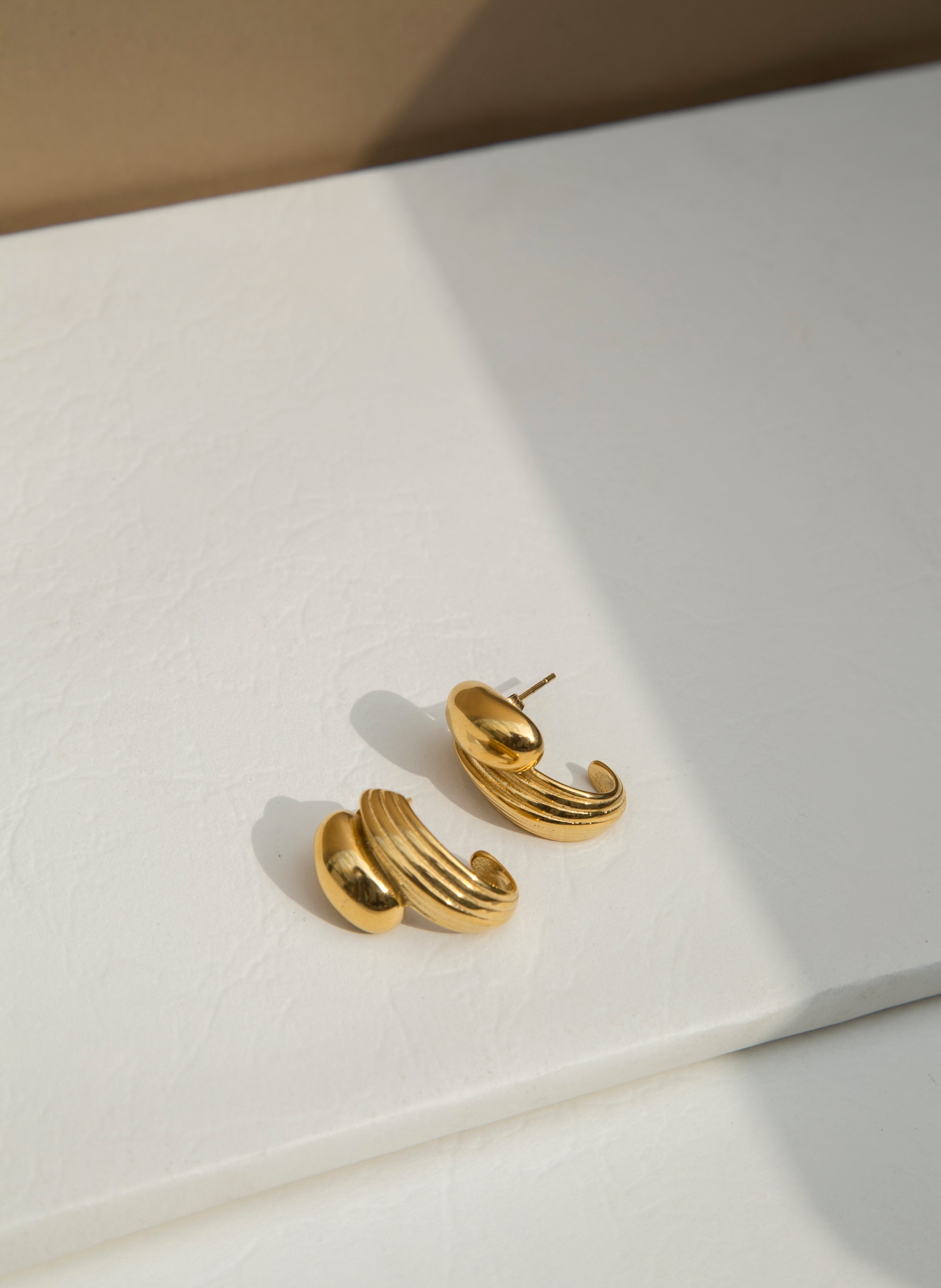 Material : Stainless Steel  - 18K Gold Plated   - Hypoallergenic   - Tarnish & Water Resistant   Dimension :Length 2.3cm   Weight : About 11g    Make a statement with our Dune Stud Earrings. The captivating spliced C-shape design, combined with a textured surface, creates a contemporary artistic touch that sets these studs apart. Bold and chunky, these statement earrings are crafted to make an impact that resonates with your modern sensibilities.