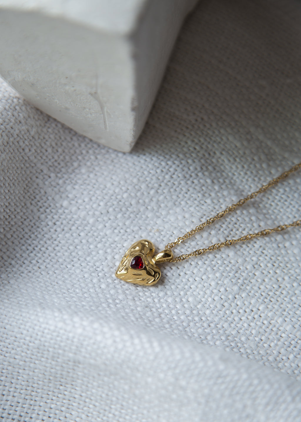 This stunning pendant, adorned with a red cubic zircon at its center, boasts a hammered texture that catches the light. The heart shape embodies love and emotion, making it a meaningful addition to your collection. Elevate your style with this exquisite statement piece