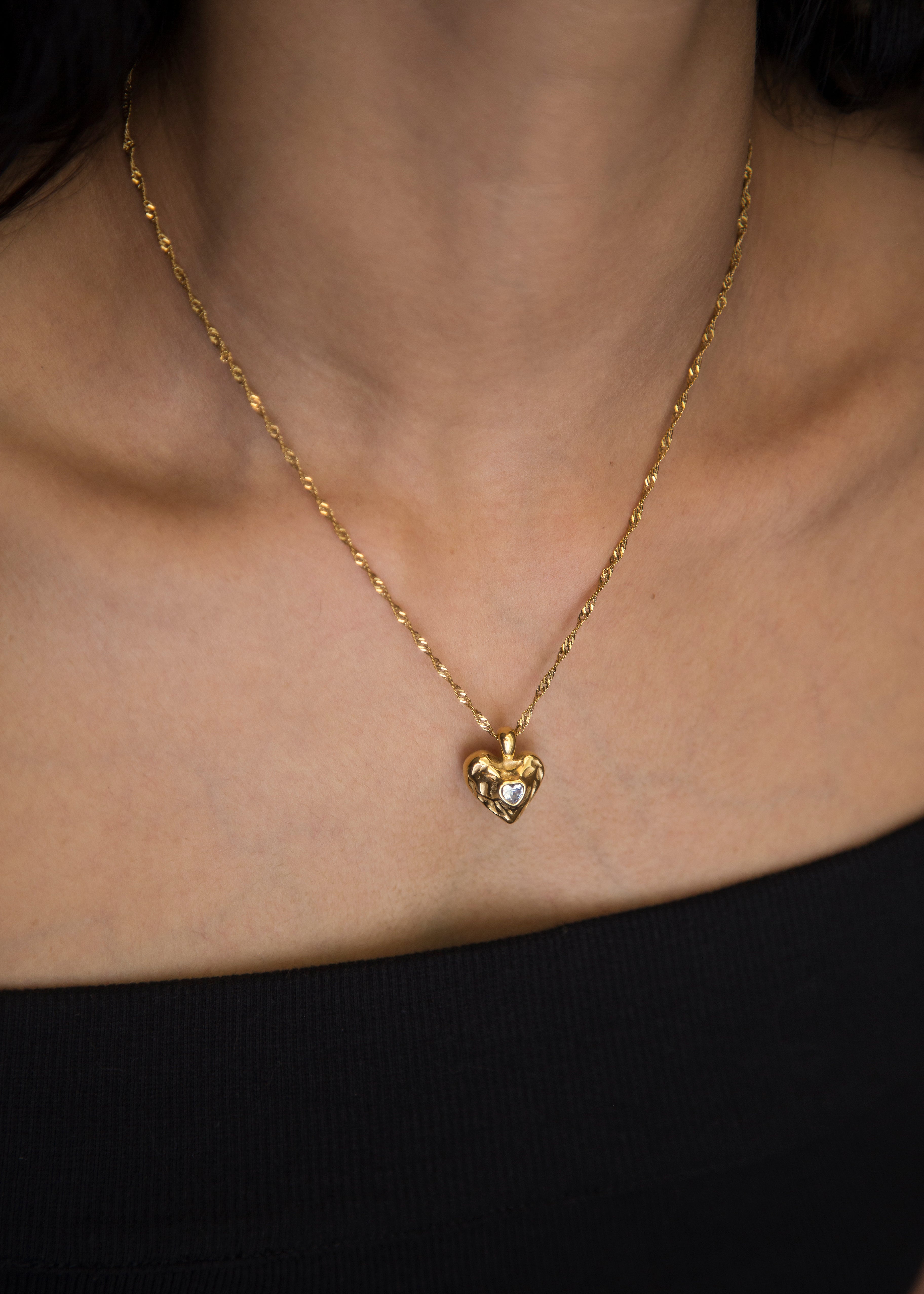 This stunning pendant, adorned with a cubic zircon at its center, boasts a hammered texture look that catches the light. The heart shape embodies love and emotion, making it a meaningful addition to your collection. Elevate your style with this exquisite statement piece.